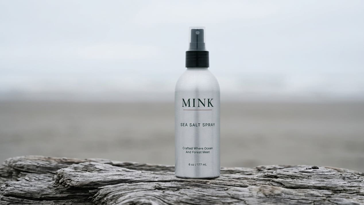 MINK Sea Salt Spray bottle on weathered driftwood at the coast